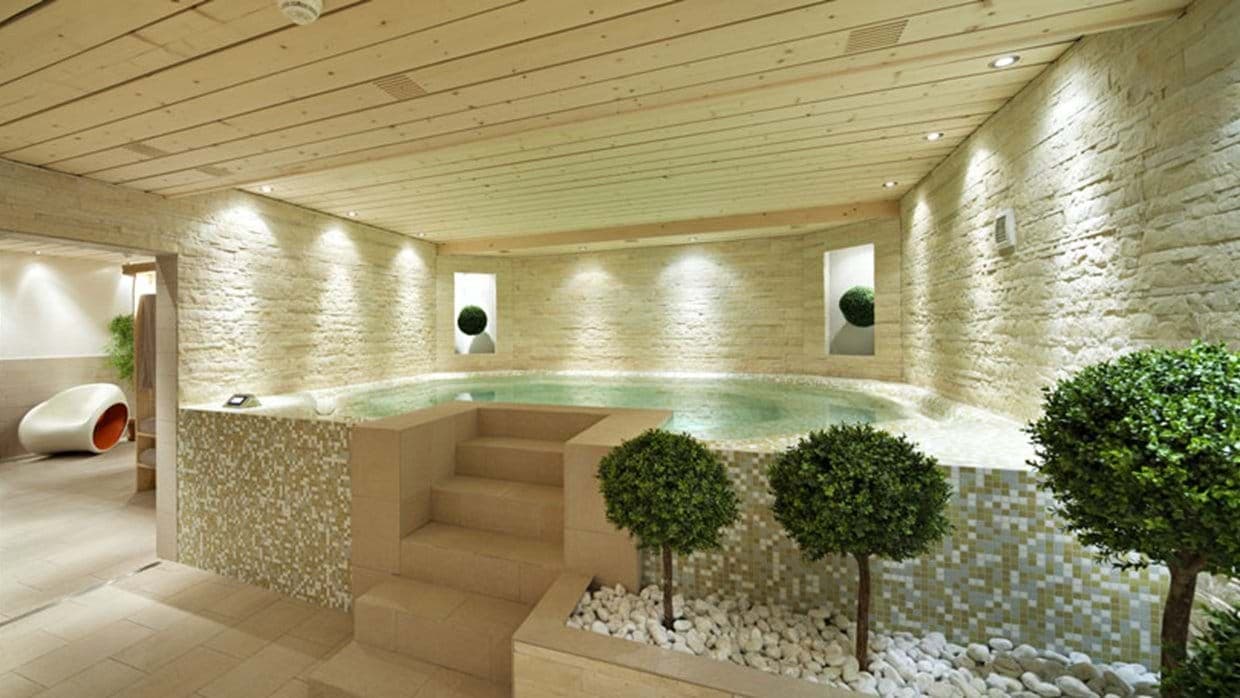 Indoor heated pool with walk-in steps and stone wall features