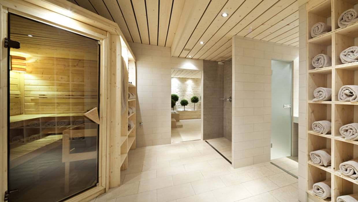 Private spa with wood-paneled sauna and walk-in rain shower