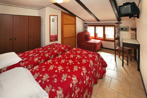 Guest bedroom with twin beds, sloped beamed ceiling, and desk