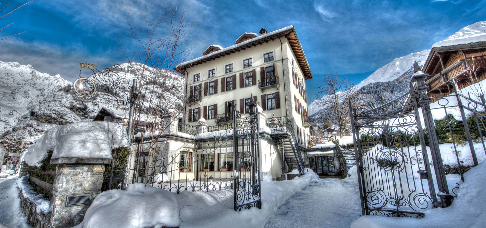 Four-story villa exterior with wrought-iron gated entrance and mountain backdrop