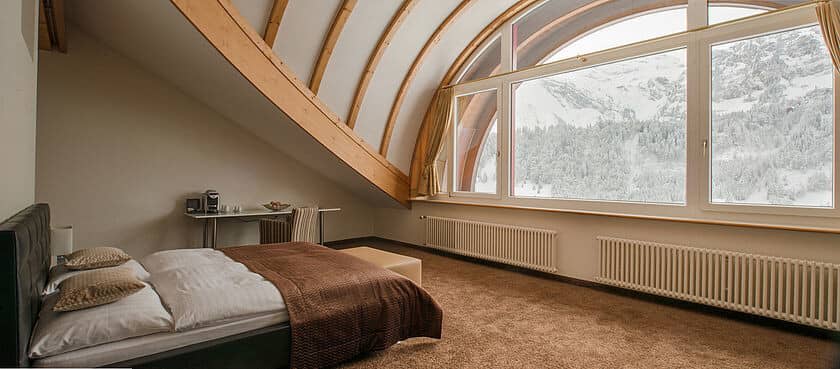 Bedroom with vaulted wood beams and snowy mountain views