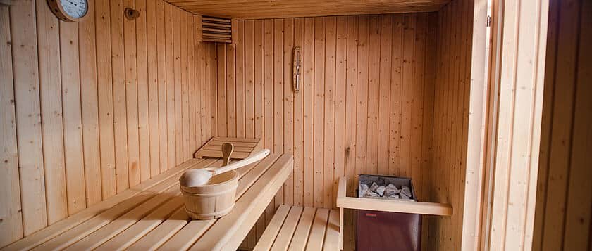 Private sauna with multi-level bench seating and bucket with ladle