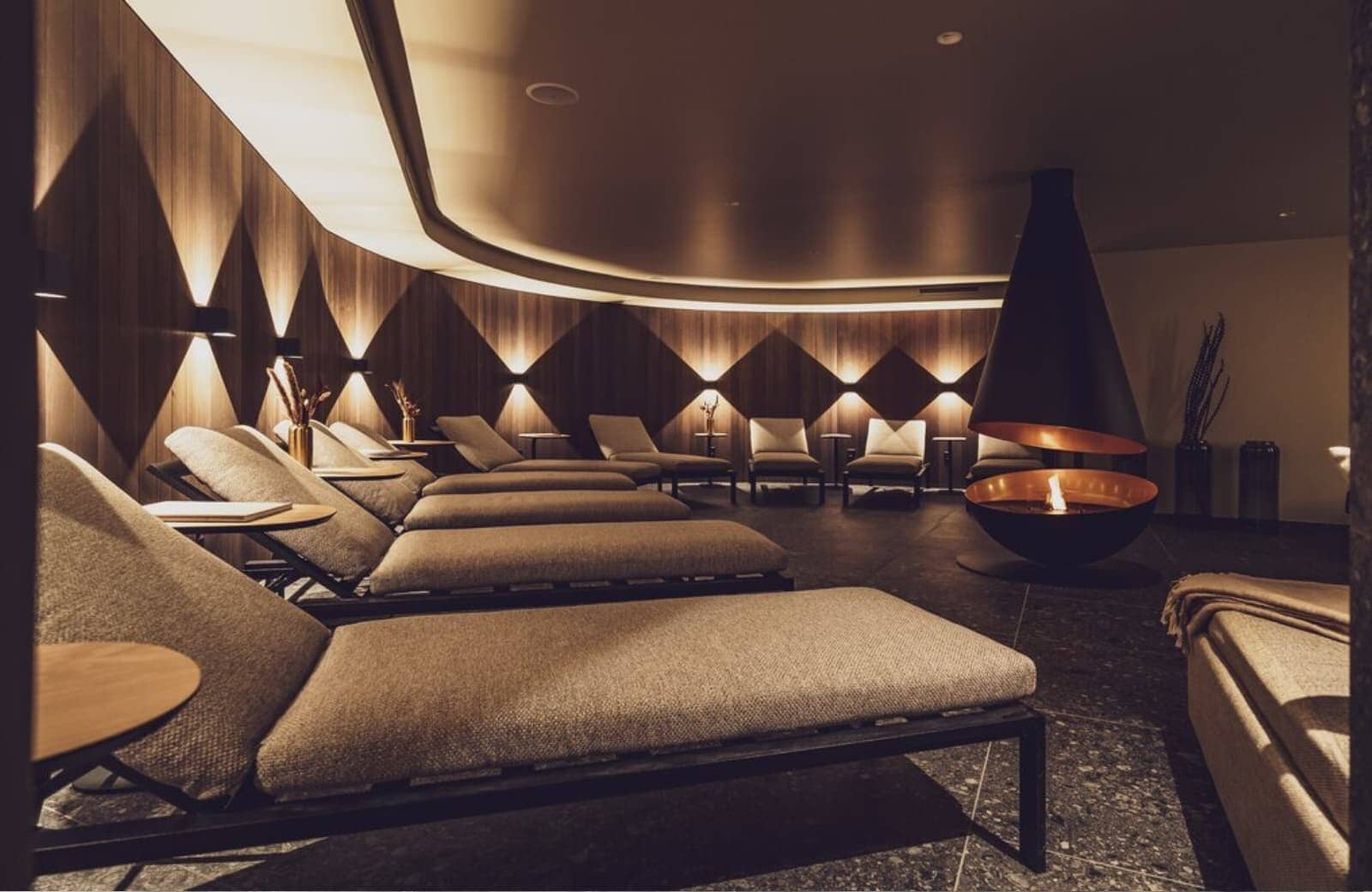 Spa lounge with suspended wood-burning fireplace and 10 chaise loungers