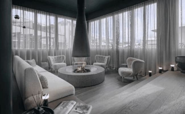 Lounge featuring central suspended fireplace and floor-to-ceiling privacy curtains