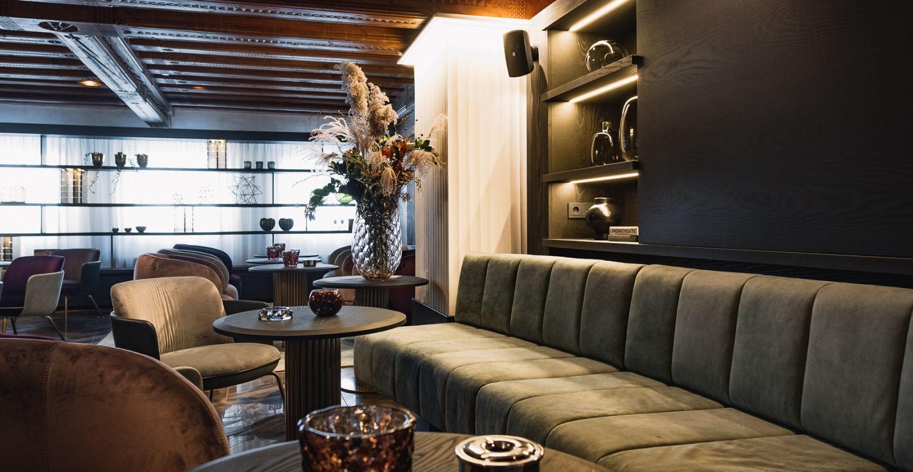 Lounge with velvet channel-tufted sofa and wood-beamed ceiling