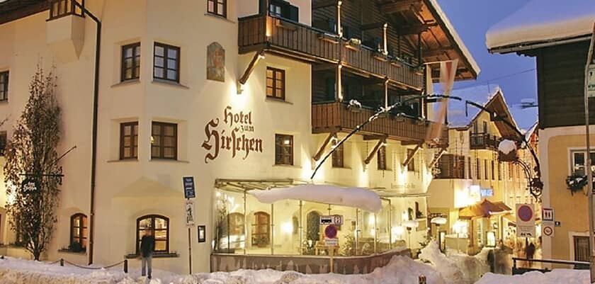 Hotel Hirschen exterior with glass-enclosed dining patio and upper floor balconies