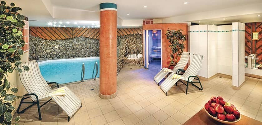 Indoor pool area with sauna, walk-in shower, and heated lounge seating