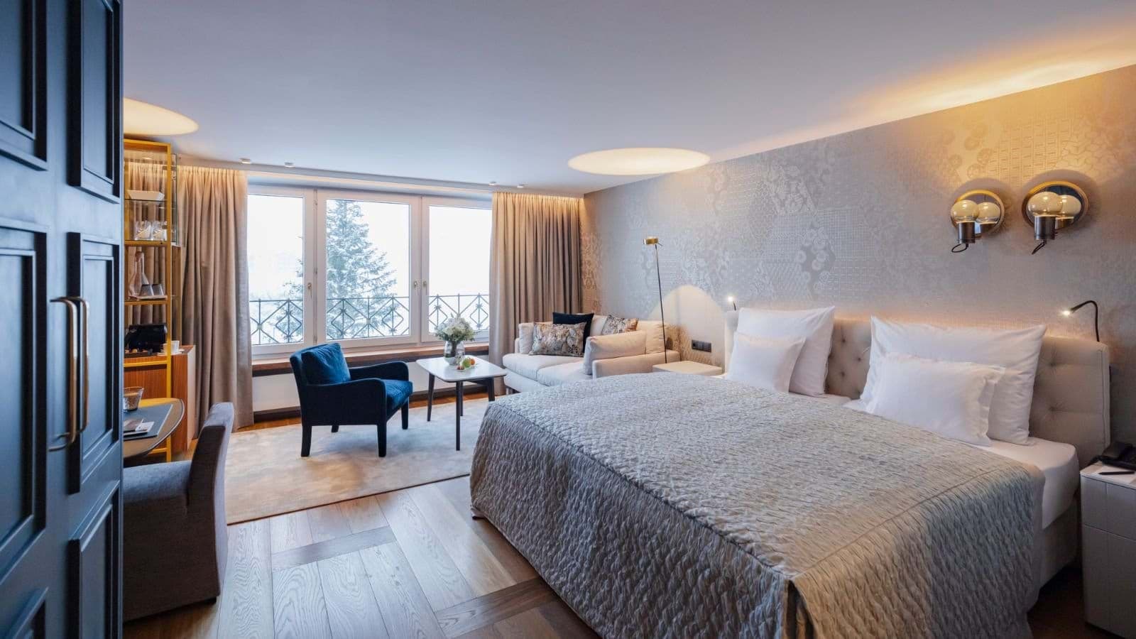 Bedroom with king bed, sofa seating area, and forest views