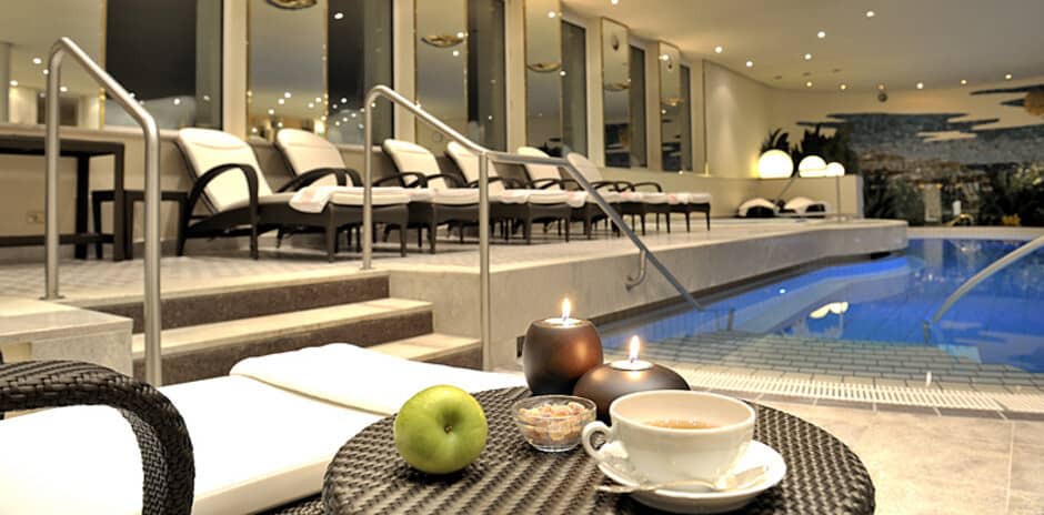 Indoor pool area with heated lounge seating and submerged step access