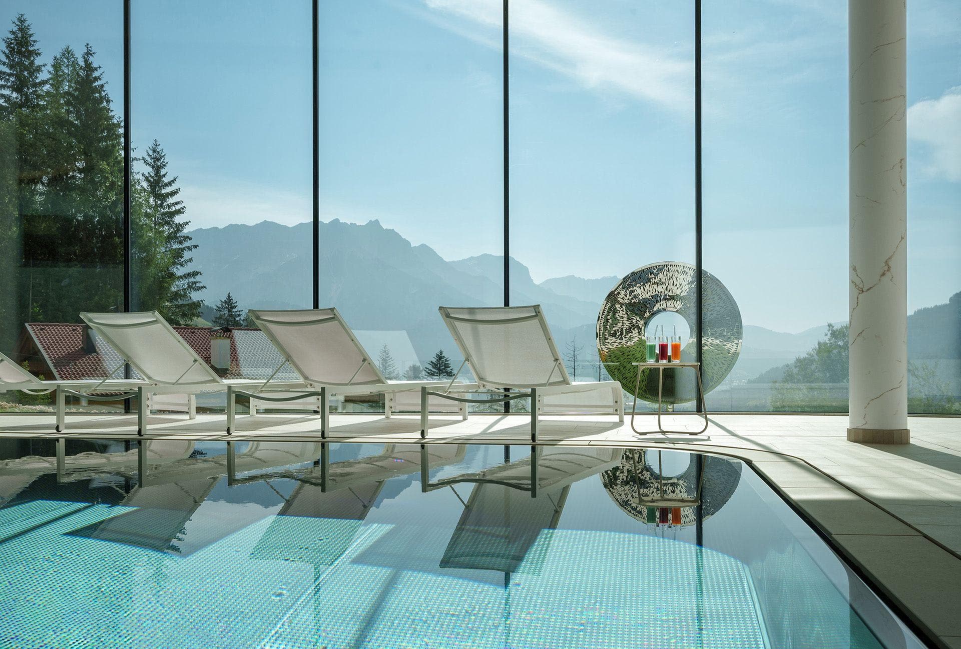 Indoor pool and lounge area with floor-to-ceiling mountain views