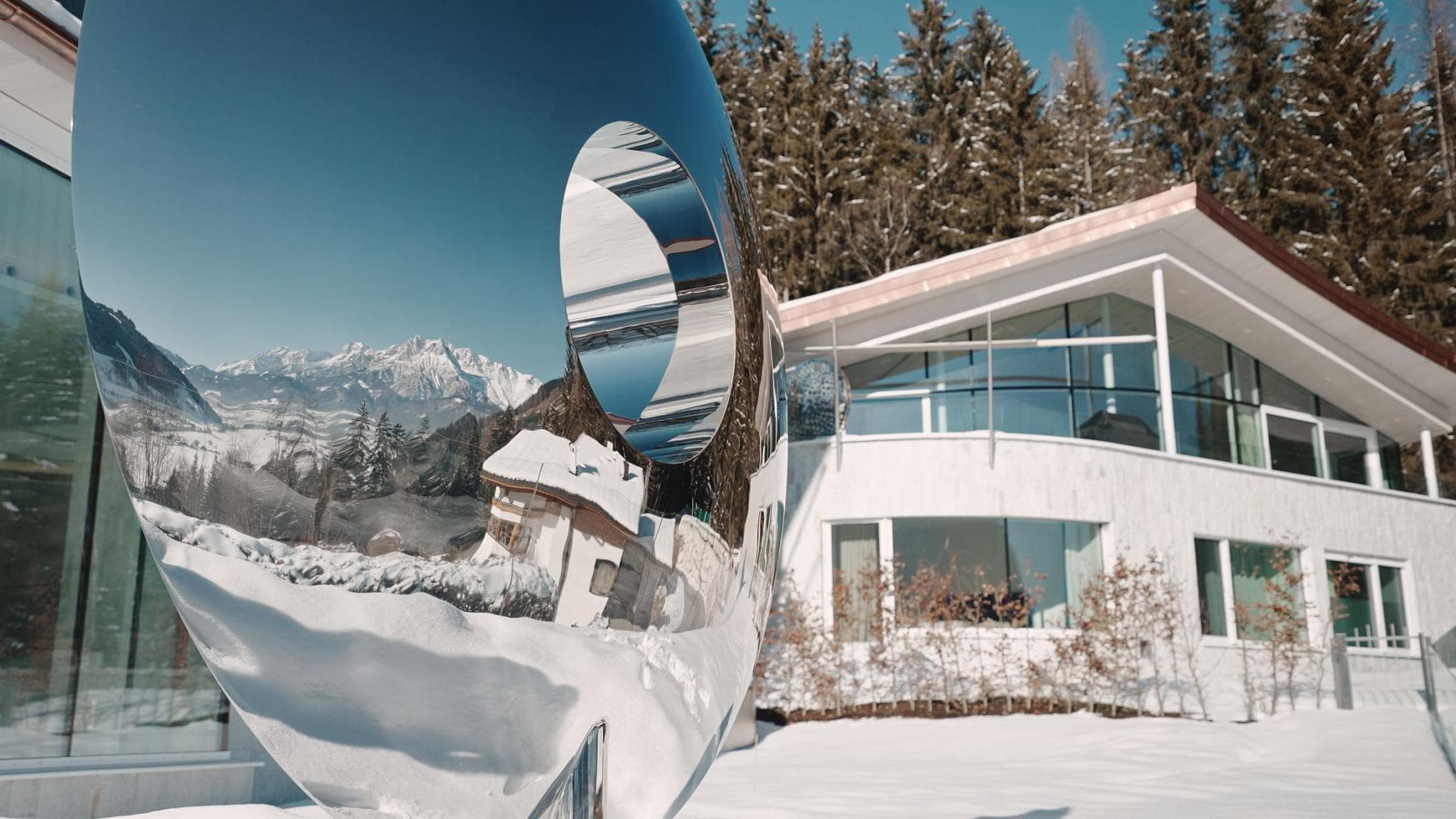 Chalet exterior featuring mirrored sculpture and panoramic alpine views