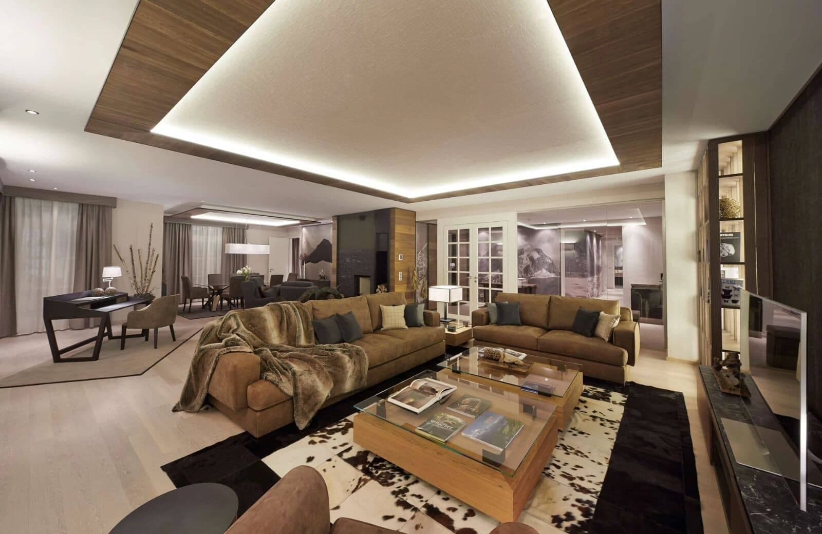 Open-plan living area with dedicated workspace and tray ceiling lighting