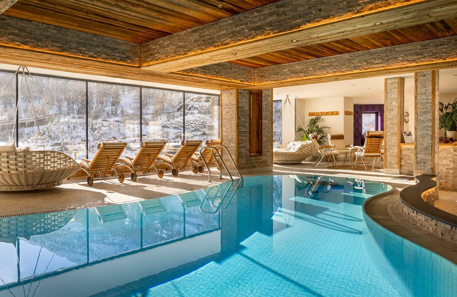 Indoor heated pool with poolside loungers and snowy mountain views