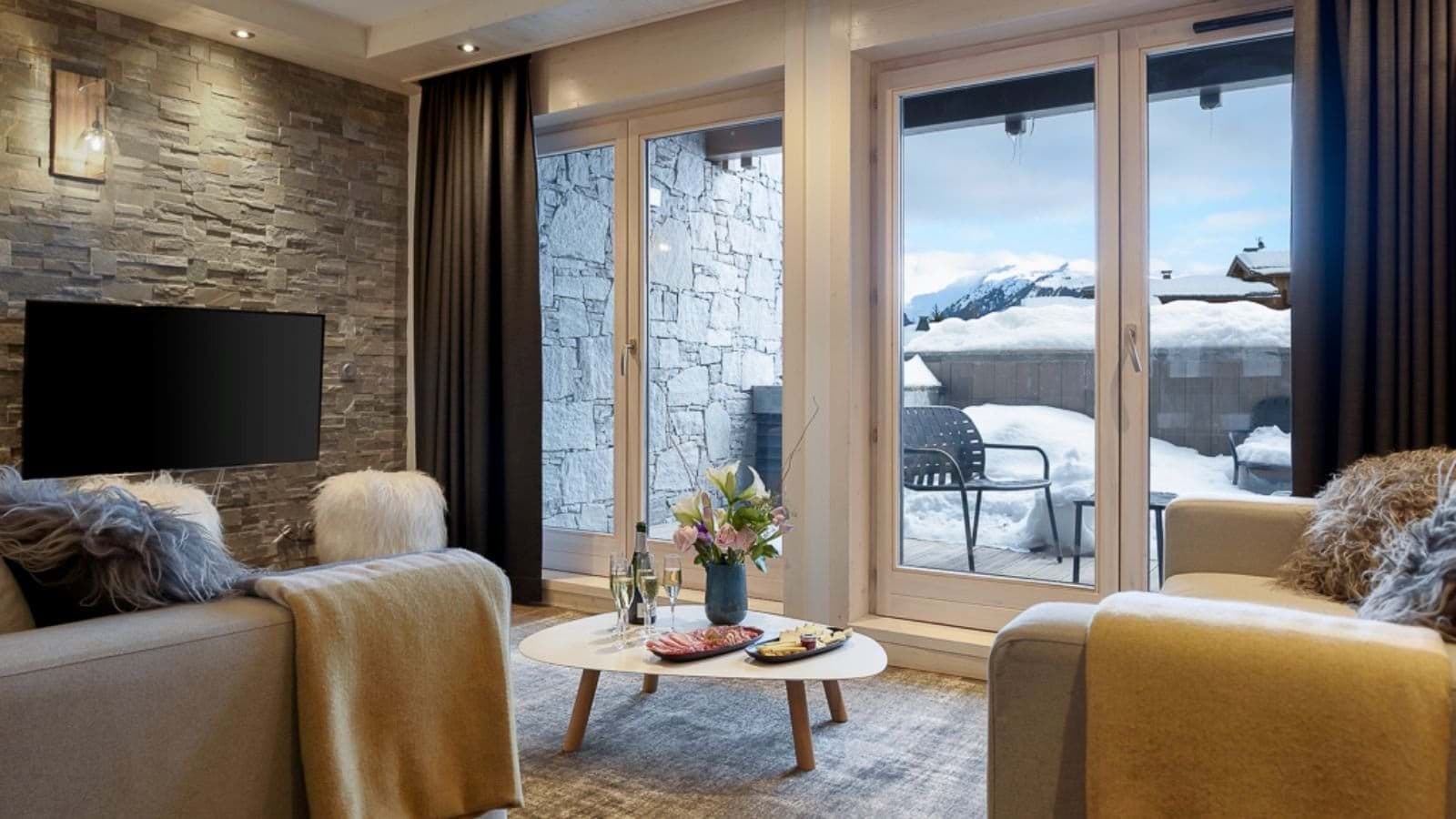Living room with mountain views; dual seating areas face TV and terrace access