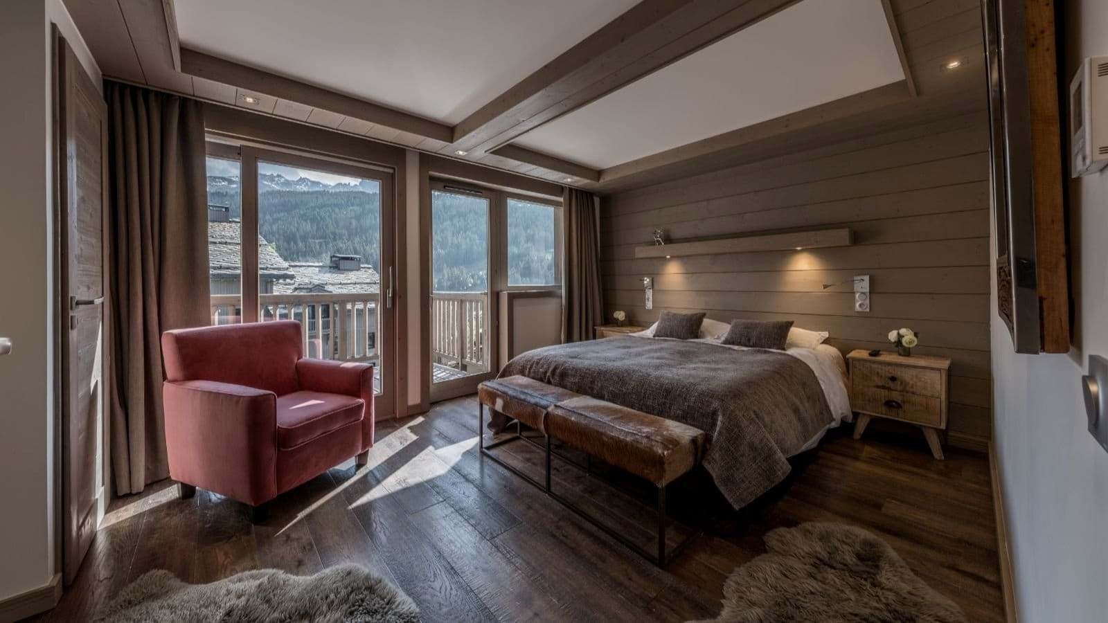 Primary bedroom with king bed, mountain-view balcony, and wood-paneled walls