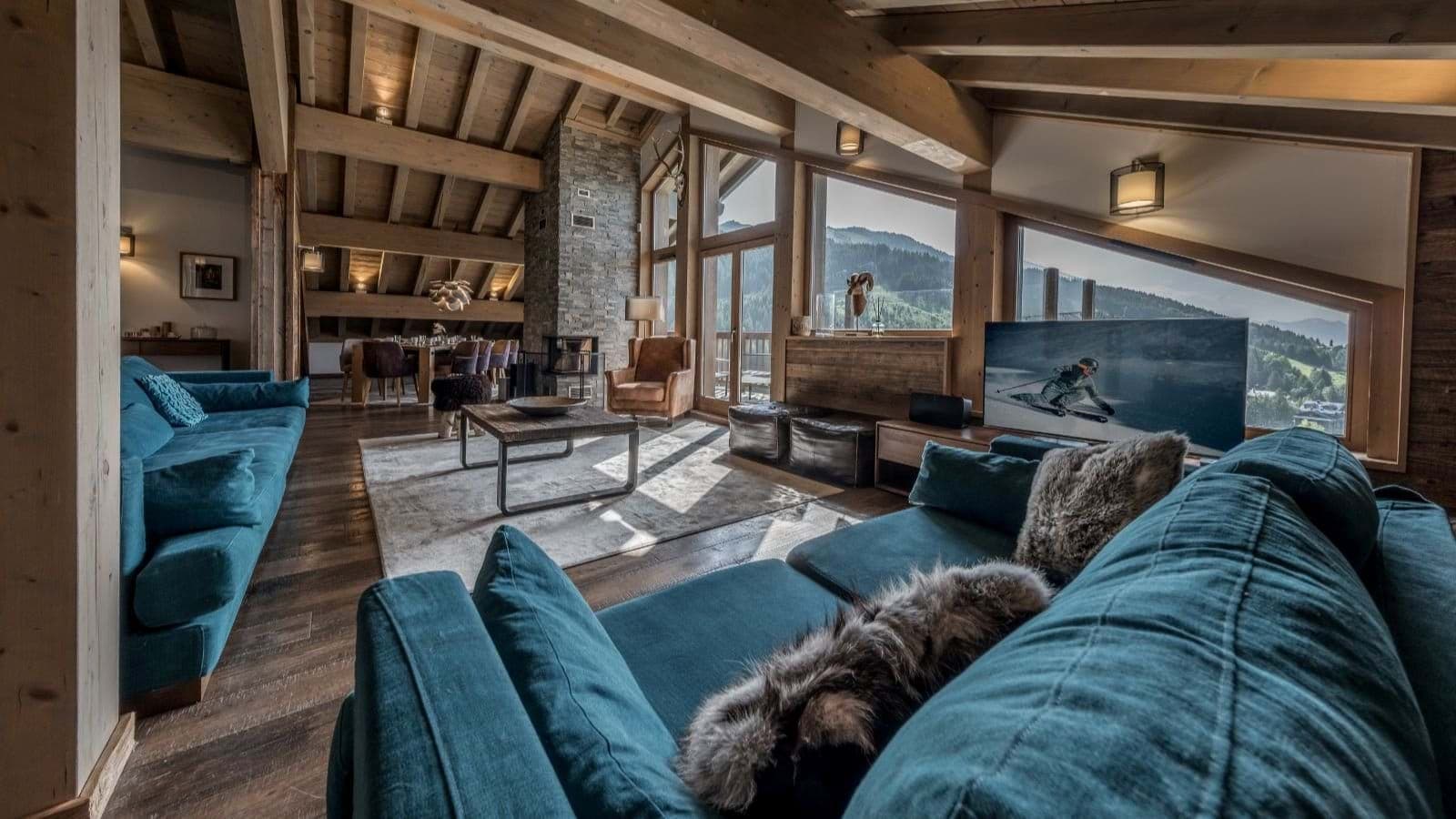 Open-plan living area with stone fireplace and mountain-view floor-to-ceiling windows
