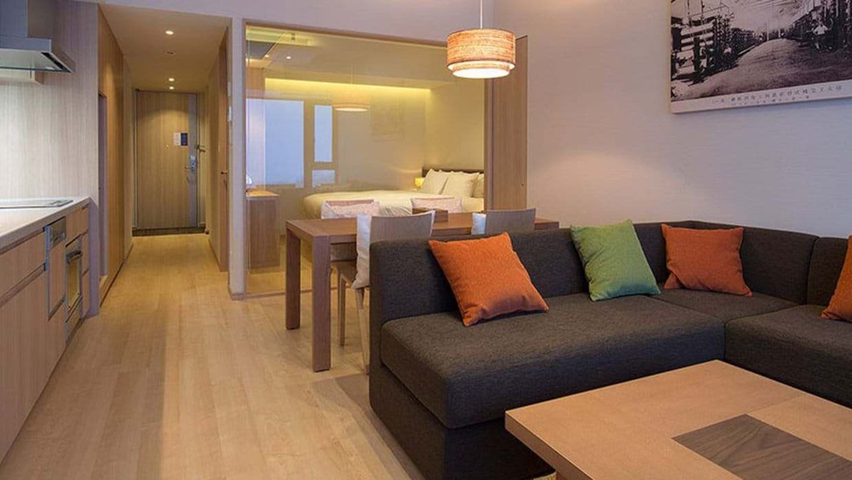 Open-plan living area with glass-walled bedroom and 4-person dining table