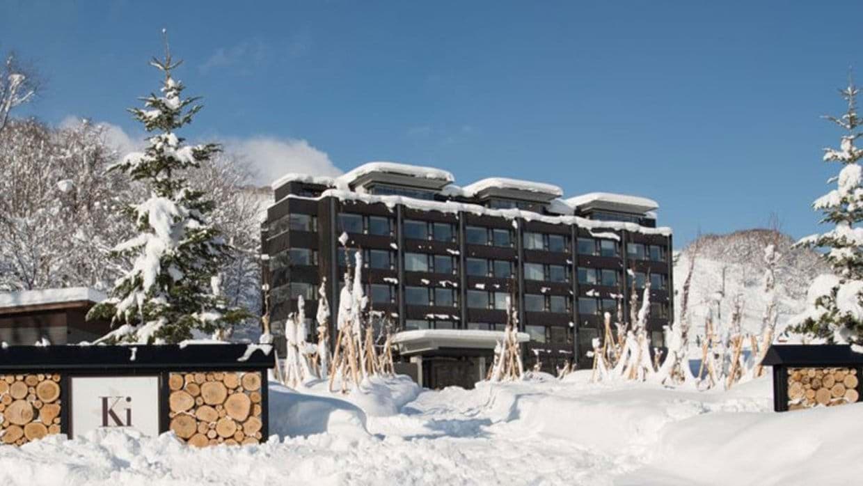 Ski-in ski-out resort exterior with snow-covered grounds and mountain backdrop