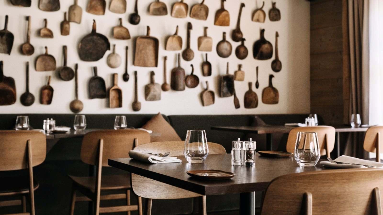 Dining area featuring banquette seating and vintage wooden utensil wall decor
