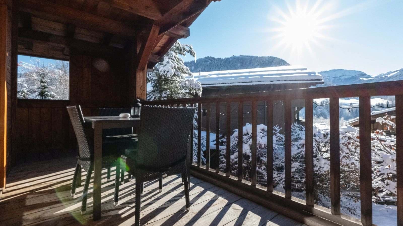 Covered wooden balcony with dining table and mountain valley views