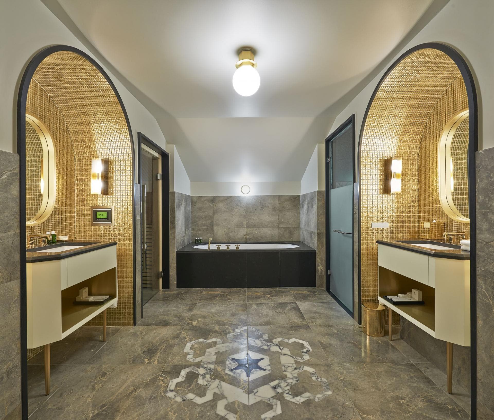 Bathroom with dual vanities, soaking tub, and gold mosaic tile alcoves
