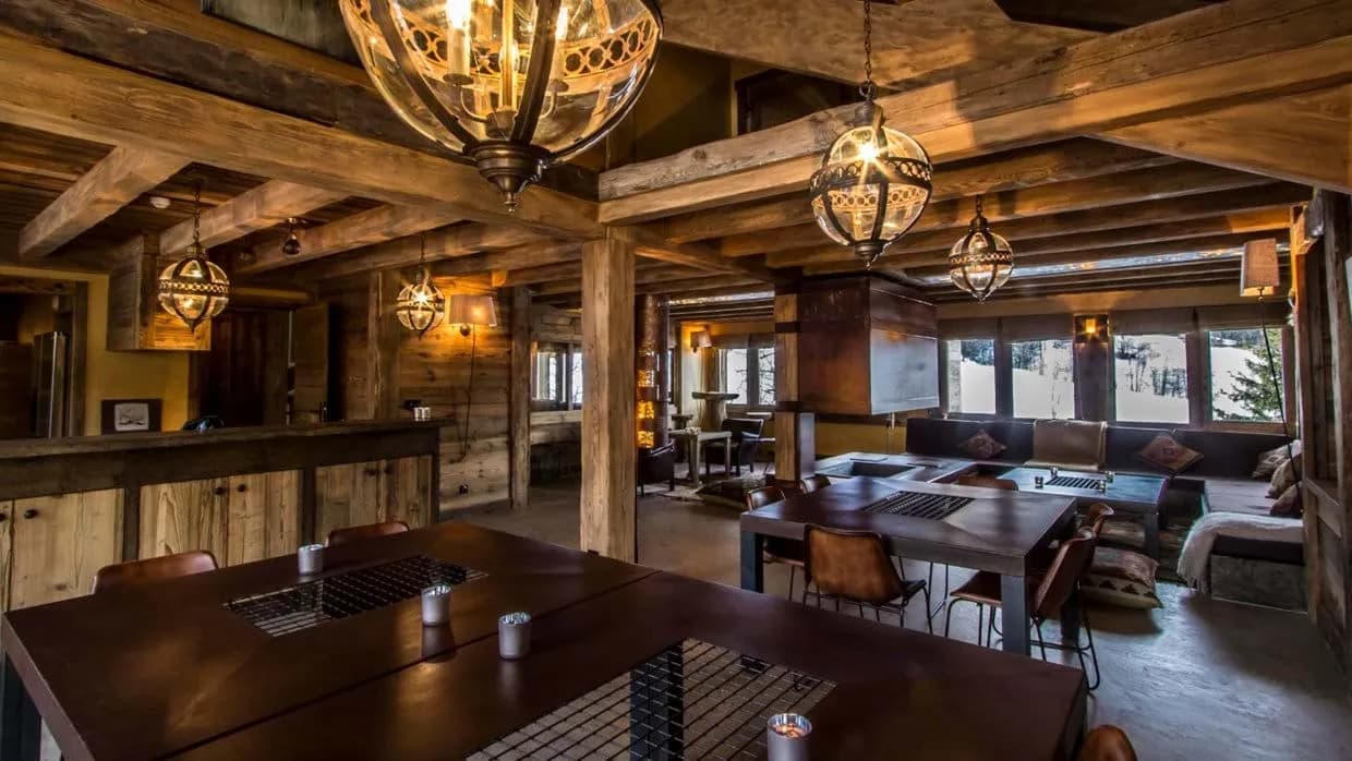 Open-plan dining and lounge area with reclaimed timber beams and mountain views