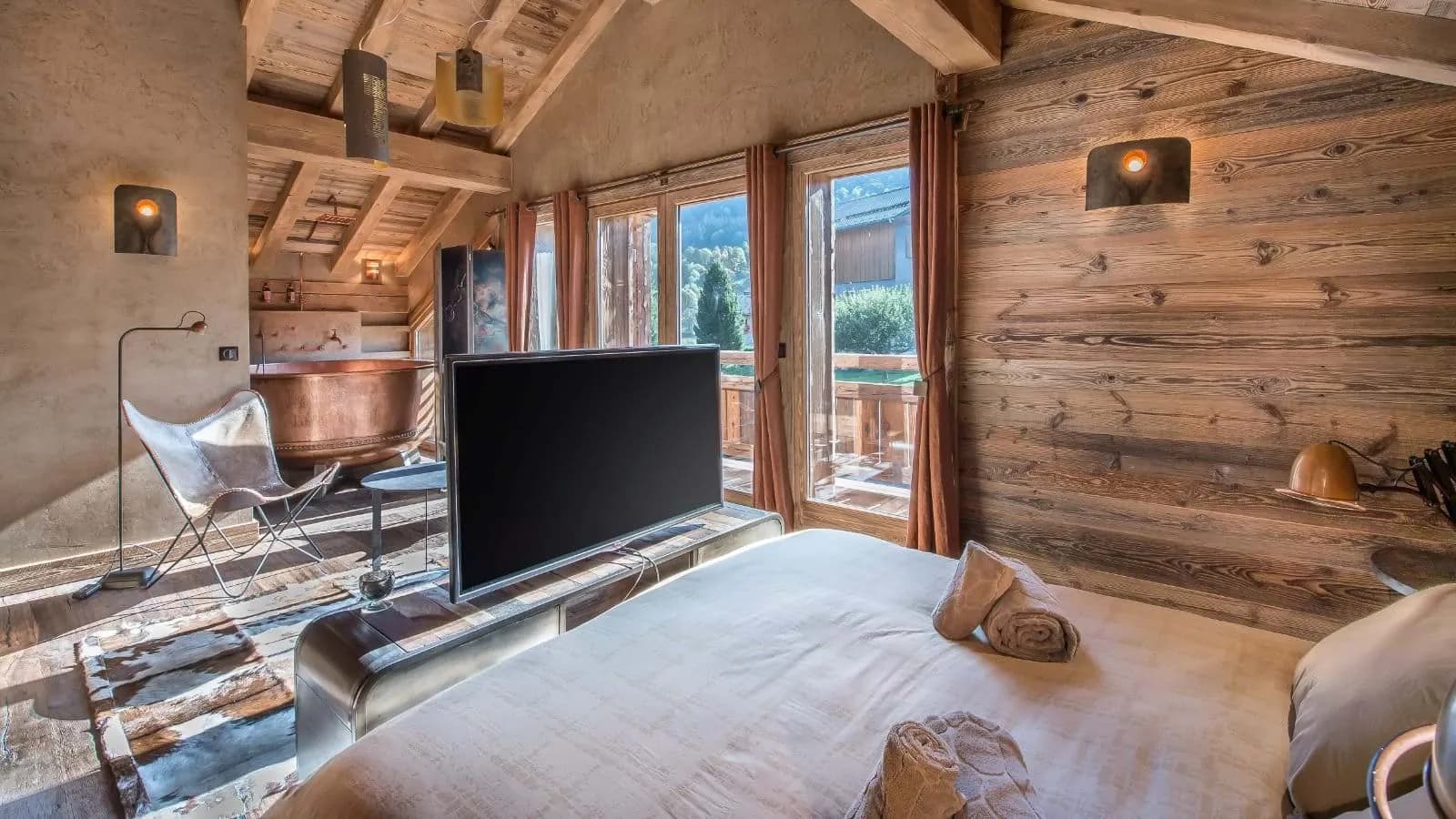 Primary bedroom featuring a copper soaking tub and pop-up television