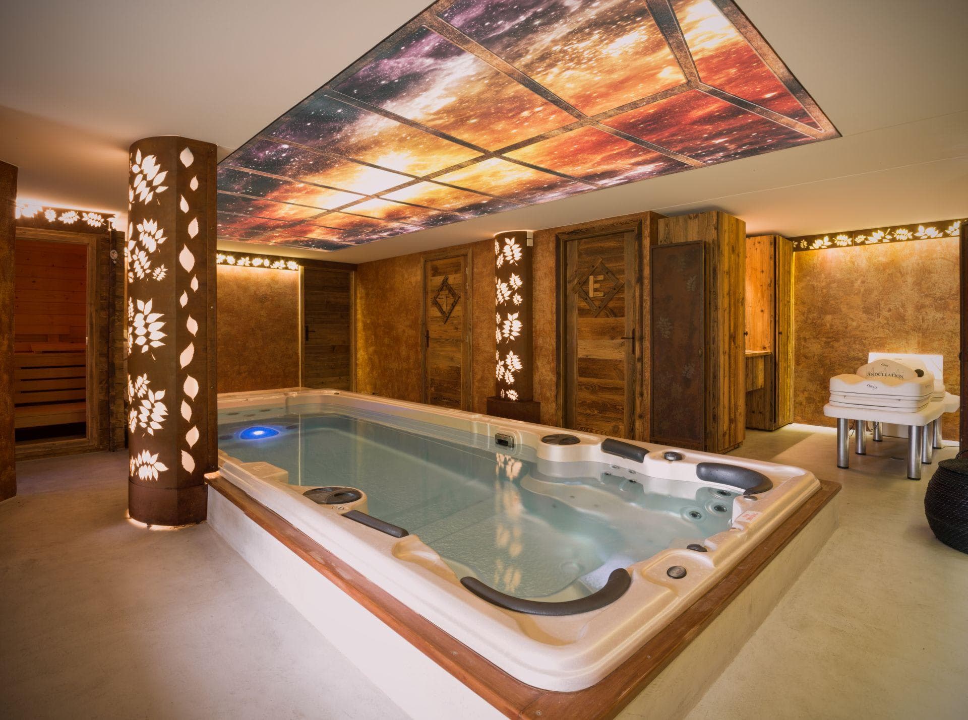 Indoor swim spa and wellness area with sauna and galaxy ceiling
