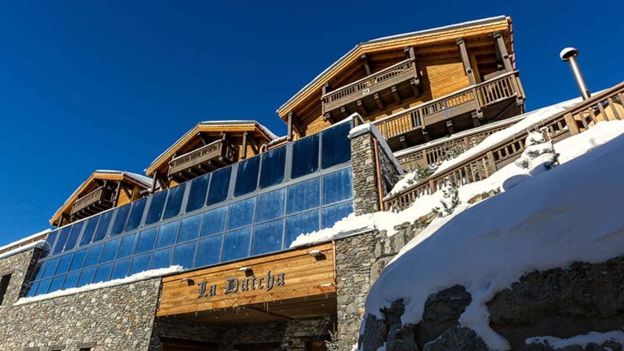 Chalet exterior featuring timber balconies and stone foundation with glass-enclosed pool