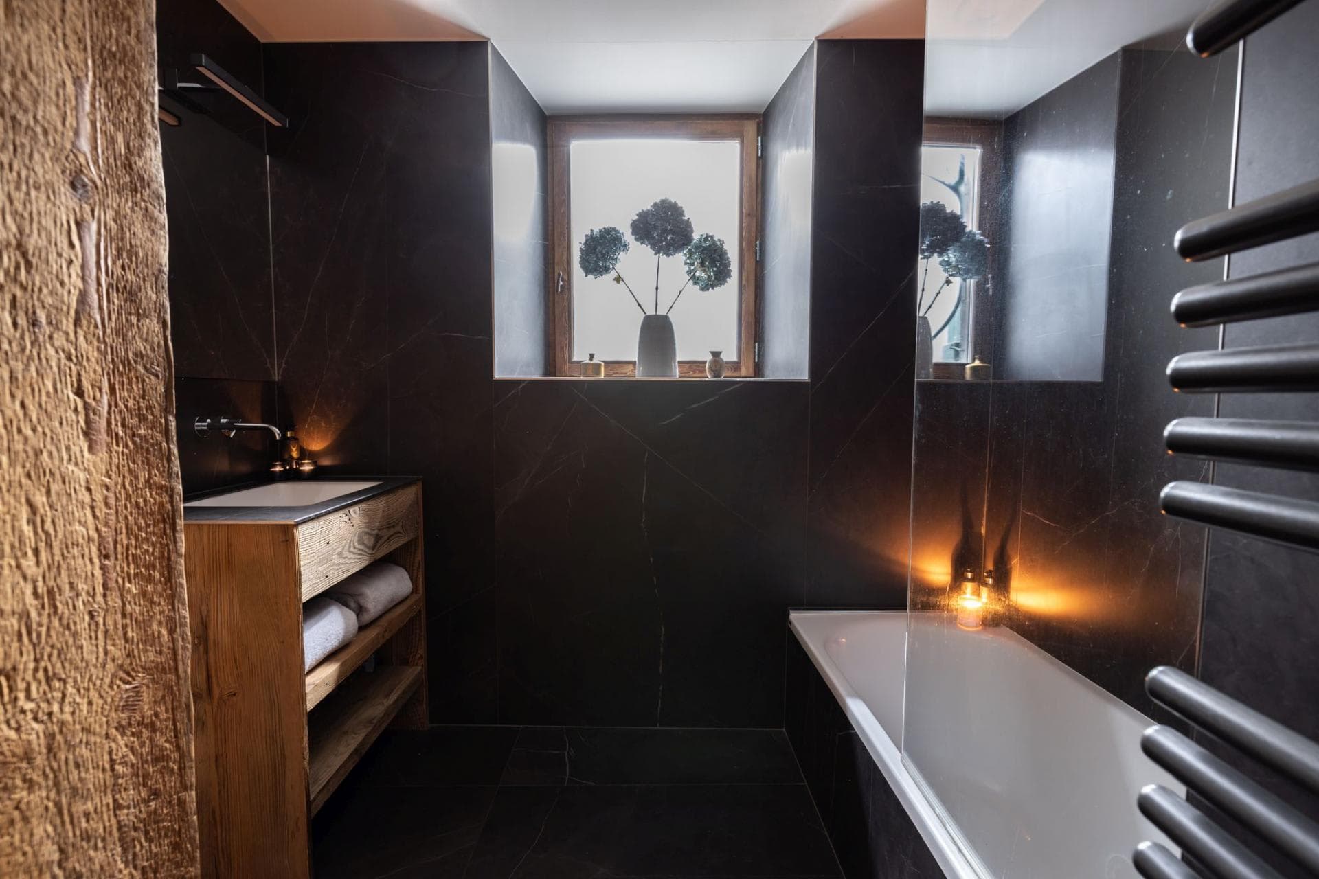 Bathroom with soaking tub, heated towel rail, and stone tiles