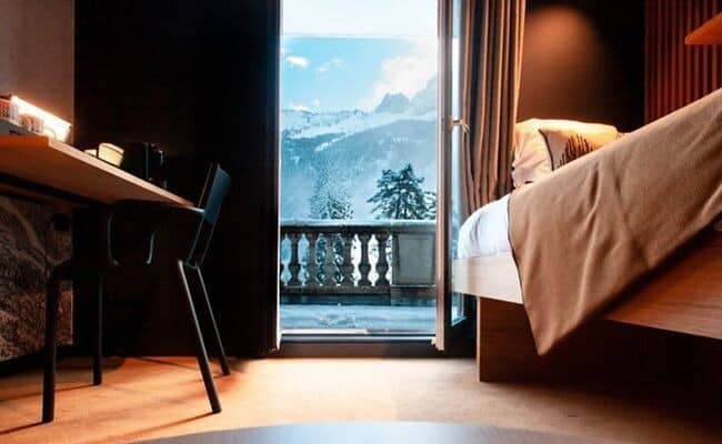 Guest bedroom with workstation and private balcony access to mountain views