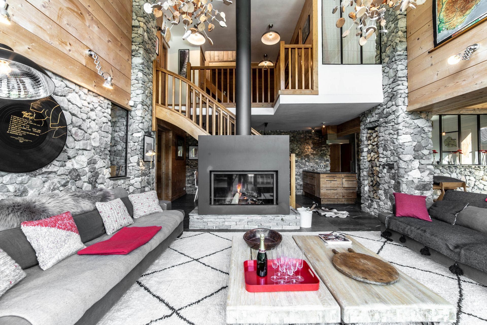 Double-sided wood fireplace with stone accents; living area and mezzanine above