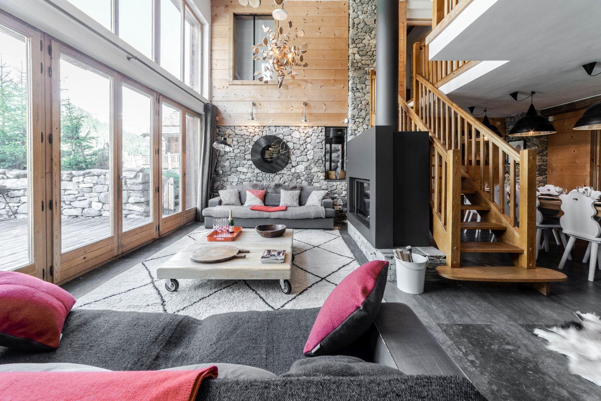 Double-height living room with central wood-burning fireplace and deck access