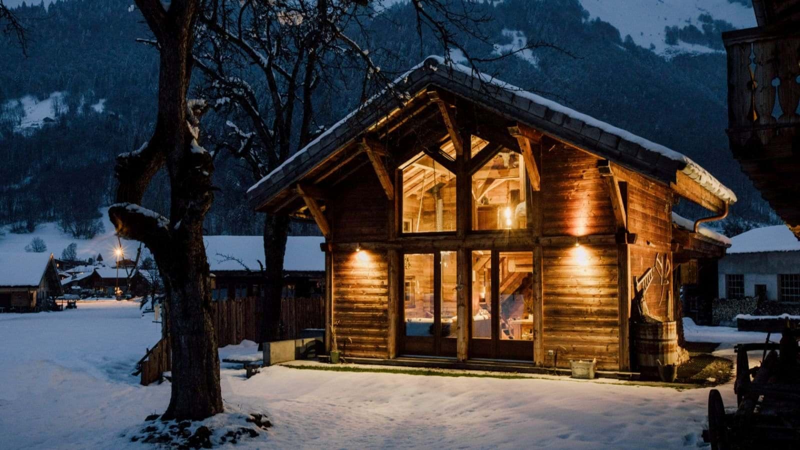 Log chalet exterior with floor-to-ceiling windows and mountain views