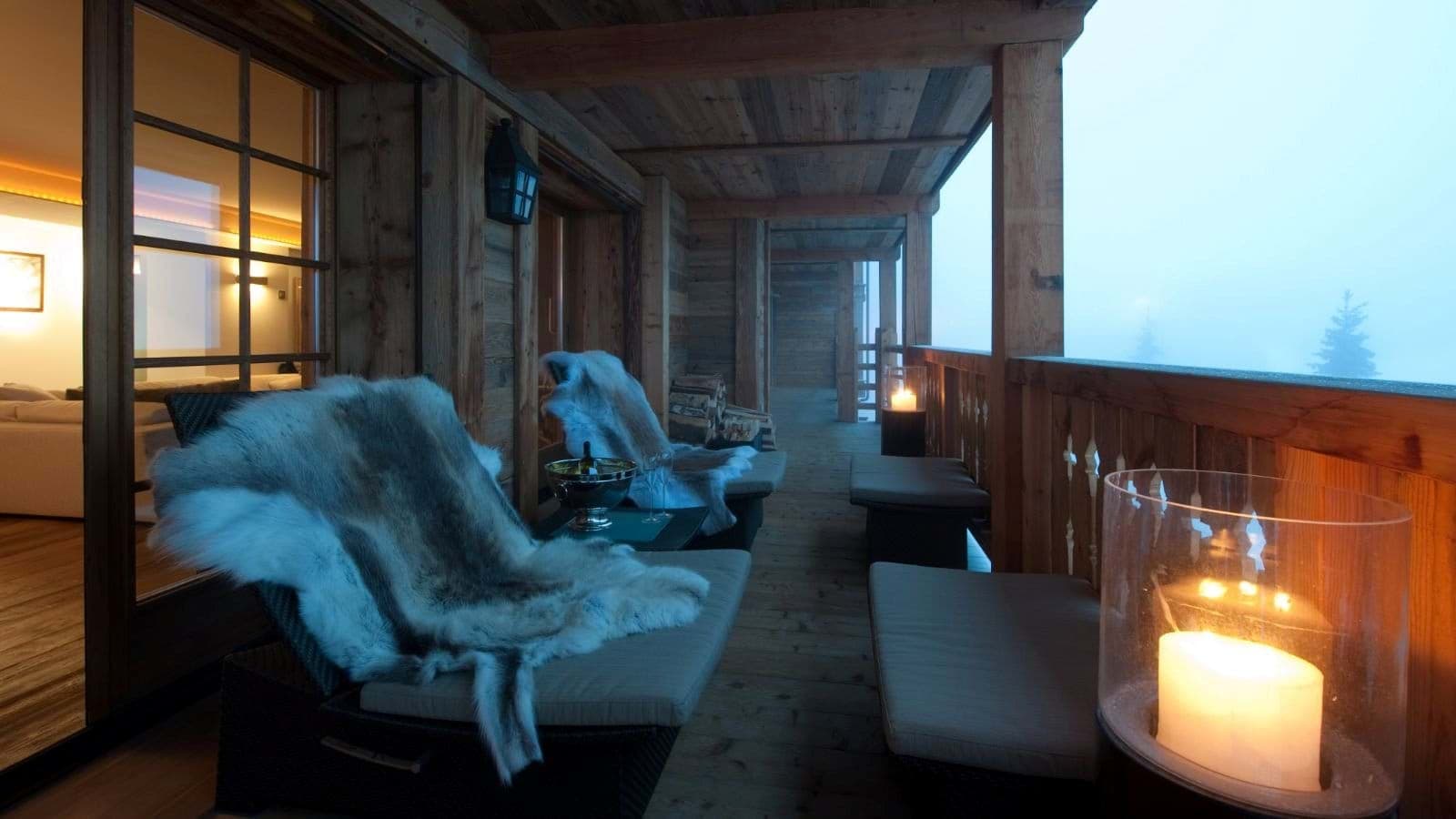 Covered balcony with lounge chairs, faux fur throws, and valley views