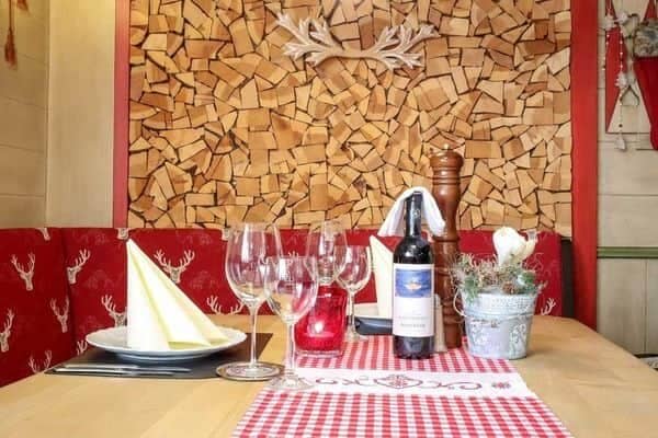 Dining nook with built-in bench seating and decorative wood stack wall