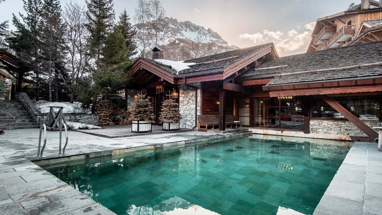 Outdoor heated pool with stone terrace and mountain views