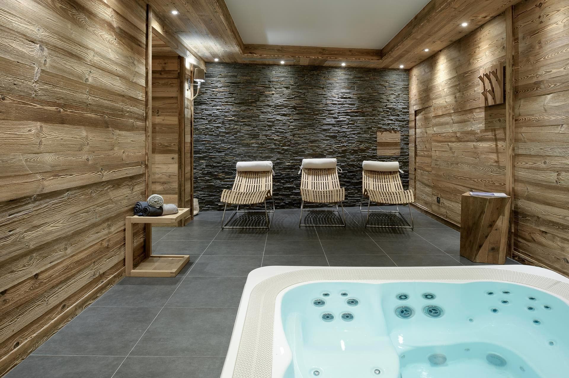 Indoor spa room with hot tub and heated wooden loungers