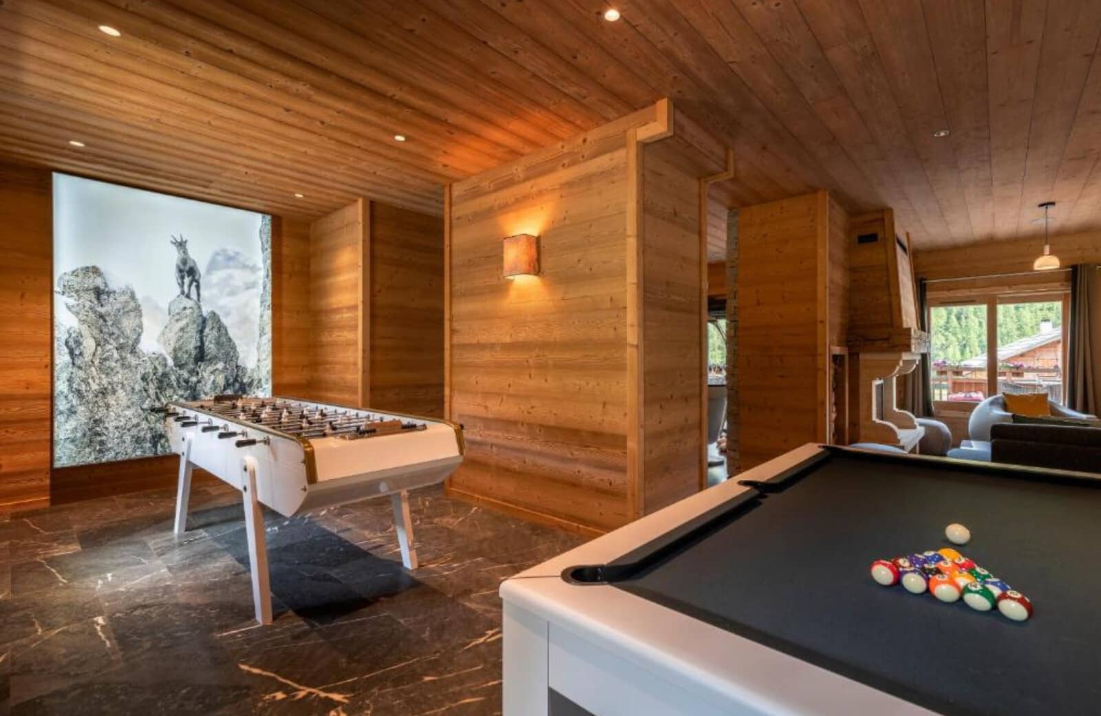 Game room with pool table, foosball, and wood-paneled walls
