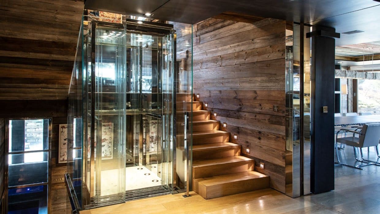 Glass elevator and wooden stairs with integrated step lighting