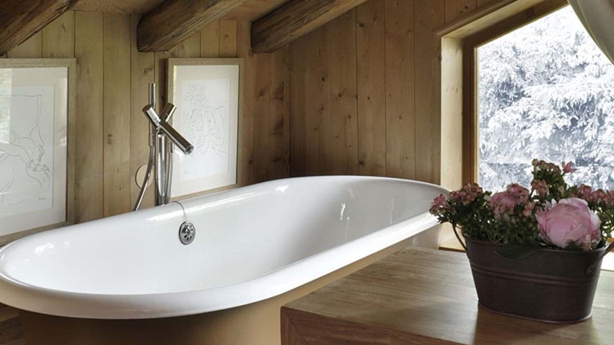 Freestanding soaking tub with wood-paneled walls and snowy forest views