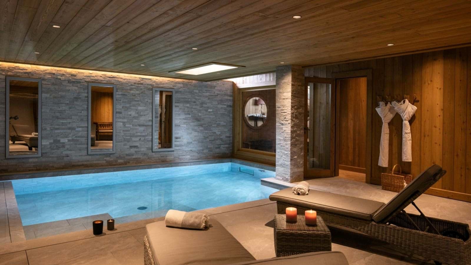 Indoor heated pool area with poolside loungers and wood-paneled ceiling