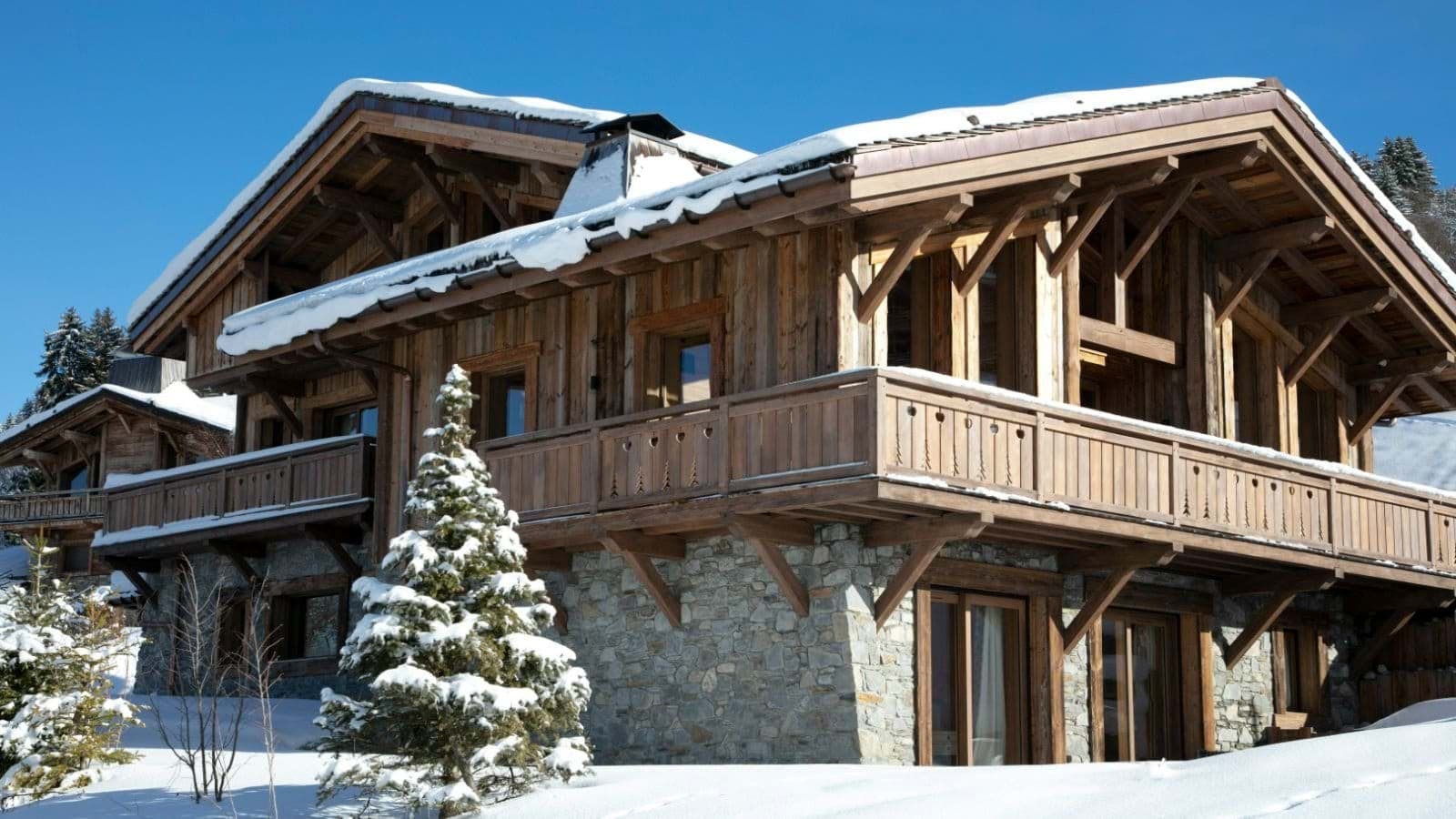 Ski-in chalet exterior with wrap-around balconies and stone-cladding