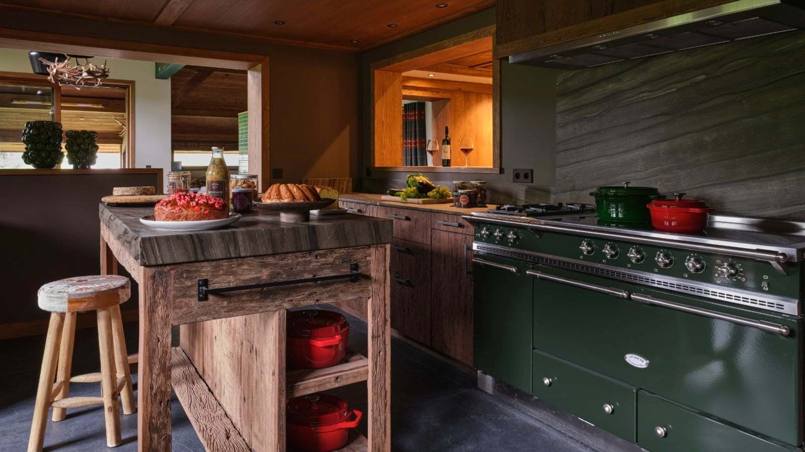 Kitchen with green Lacanche range and thick stone-topped island