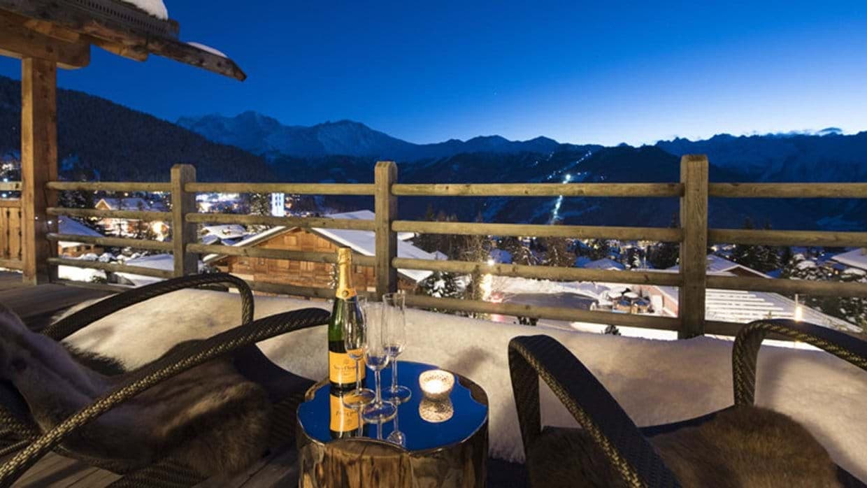Private balcony with fur-lined seating; view of illuminated ski slopes
