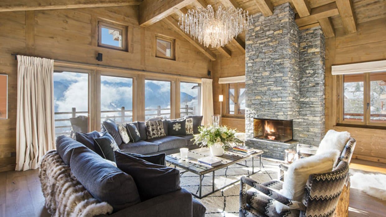 Living room with stone fireplace, vaulted timber ceilings, and mountain views