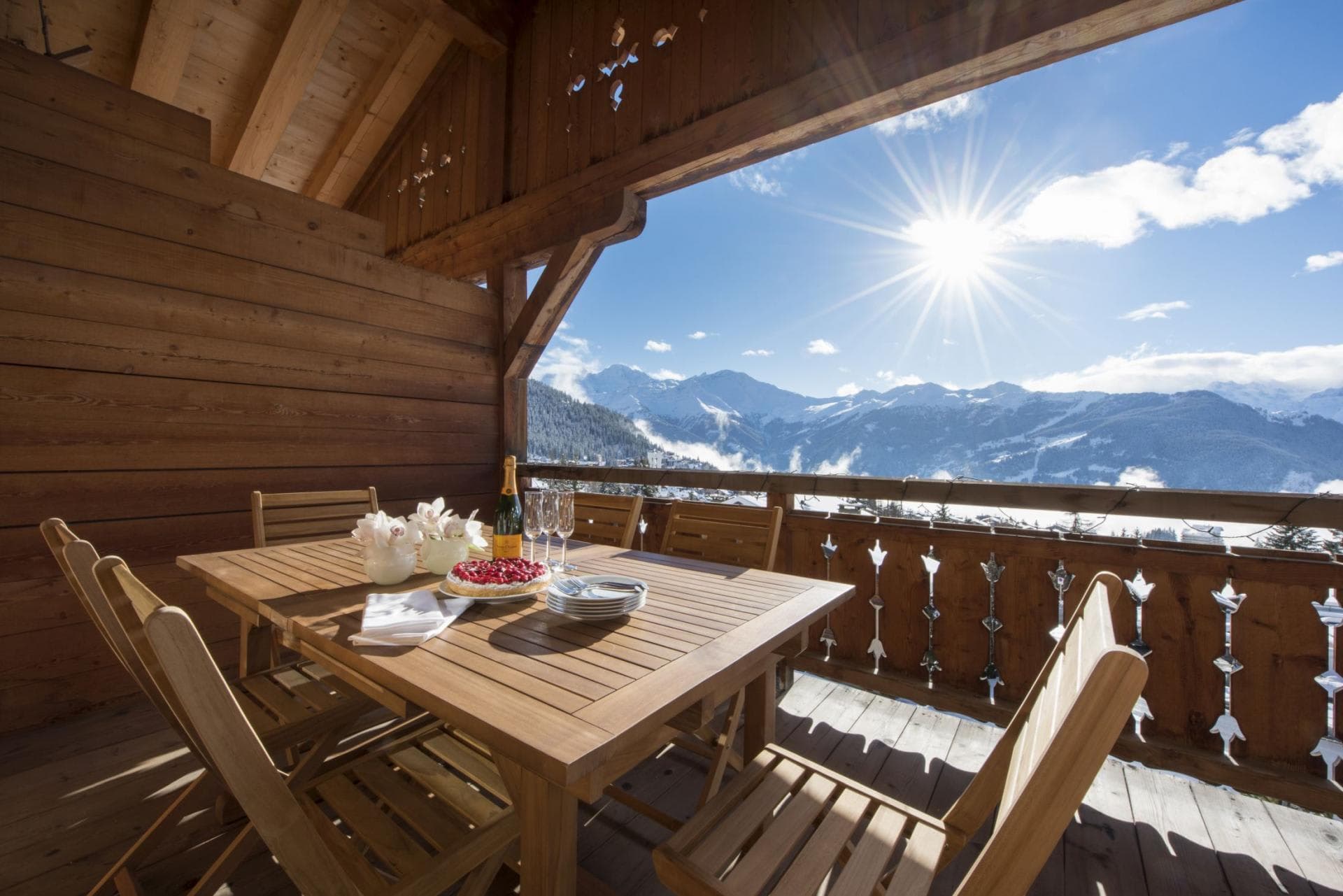 Covered wooden balcony with dining table for six and mountain views