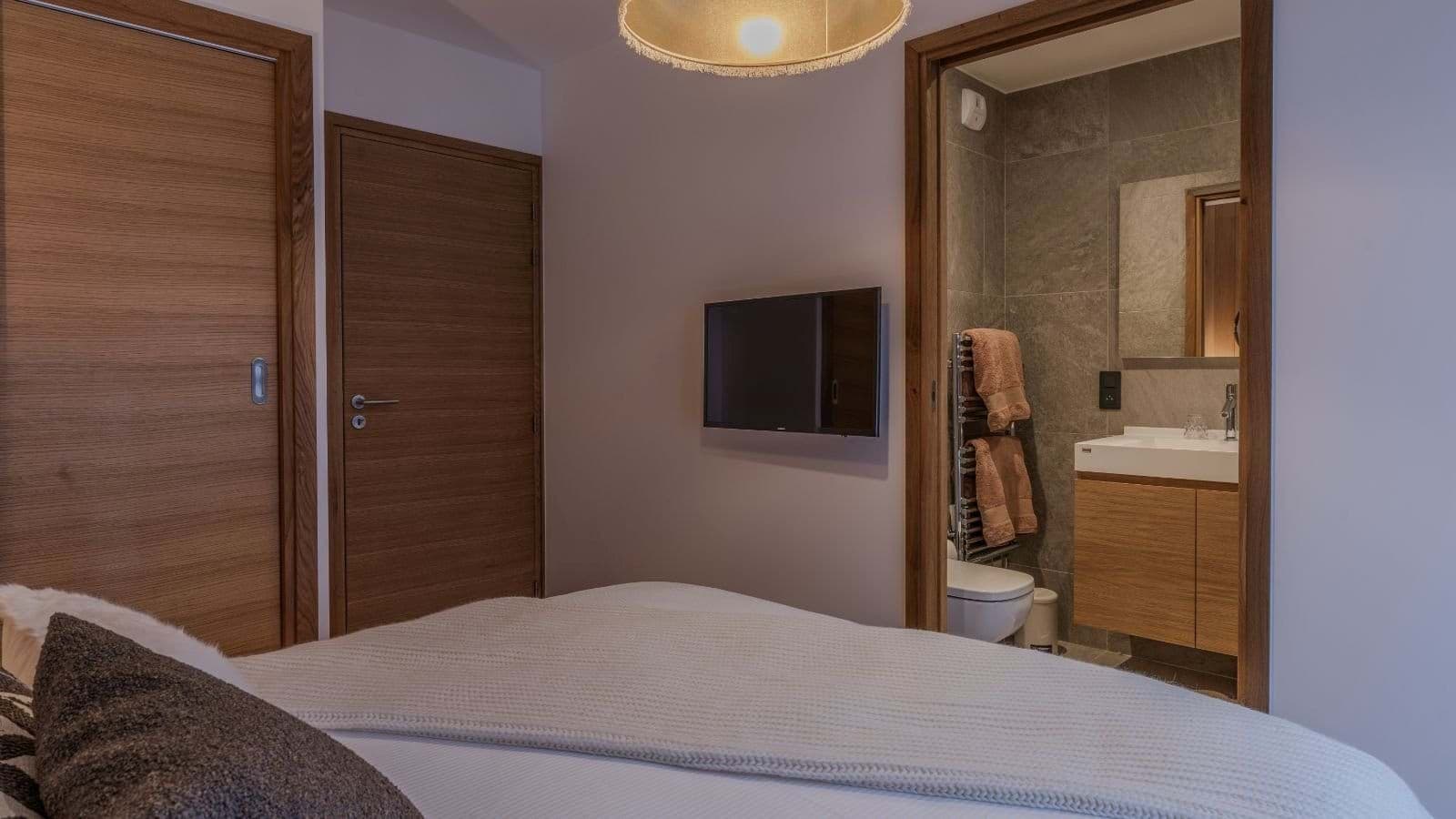 Guest bedroom with wall-mounted TV and private ensuite bathroom