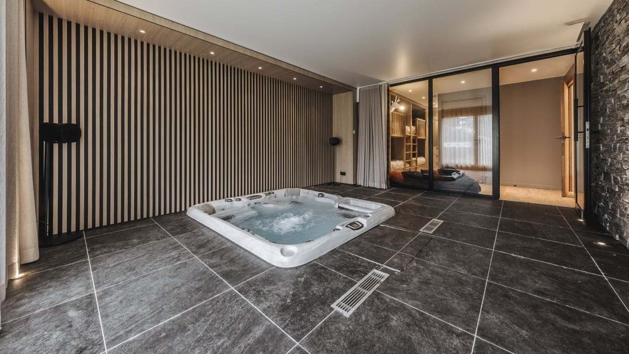 Indoor hot tub with slat wood walls adjacent to bunk room