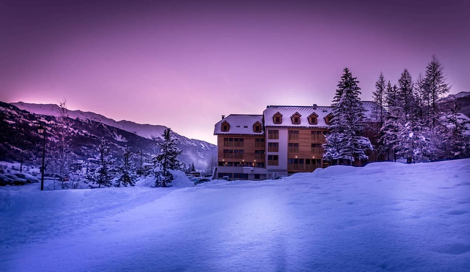 Ski-in/ski-out lodge at dusk with private balconies and mountain views